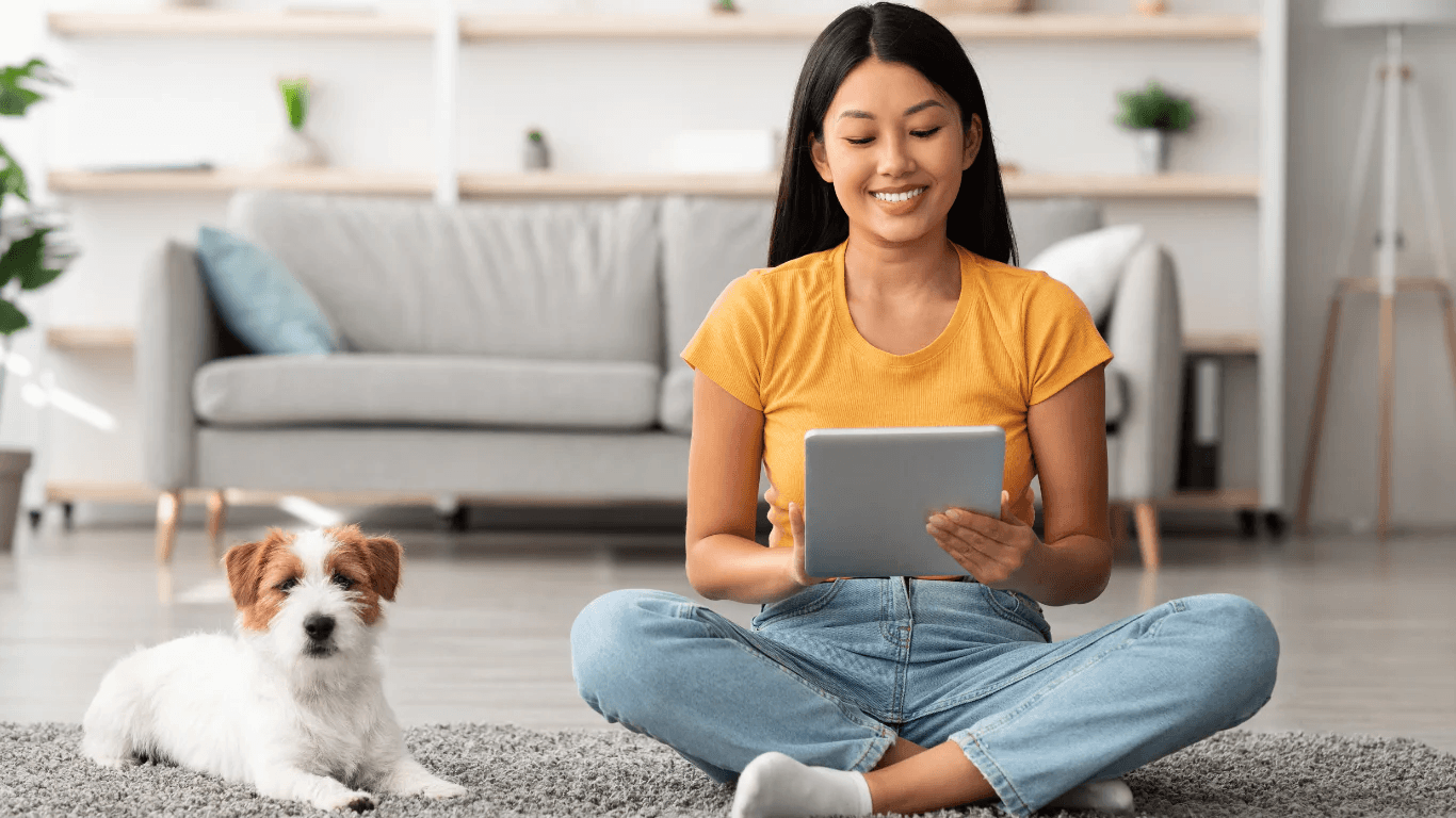 girl using tablet sitting on floor with dog