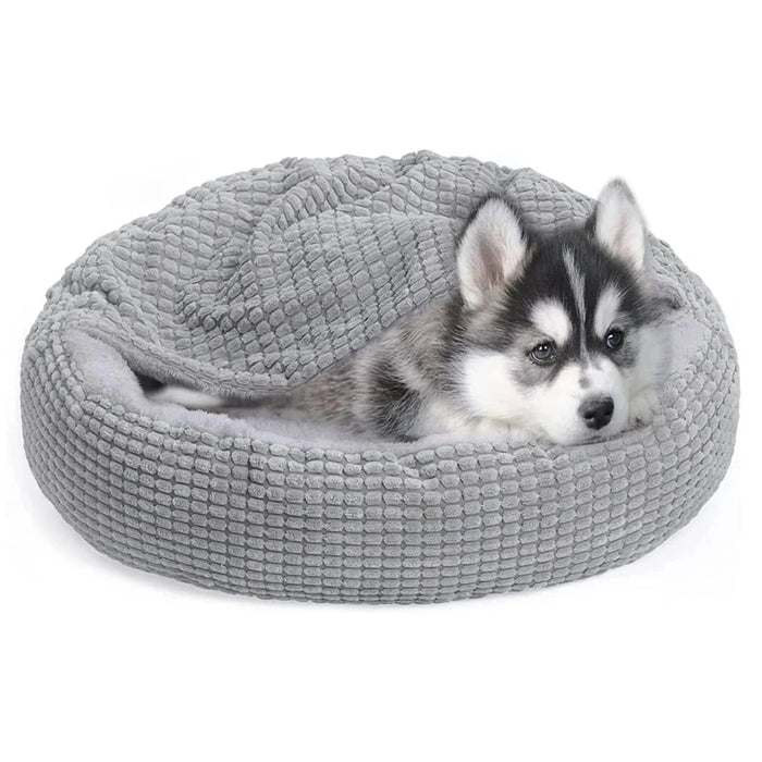 Puppy lying on a gray pet bed against a white background