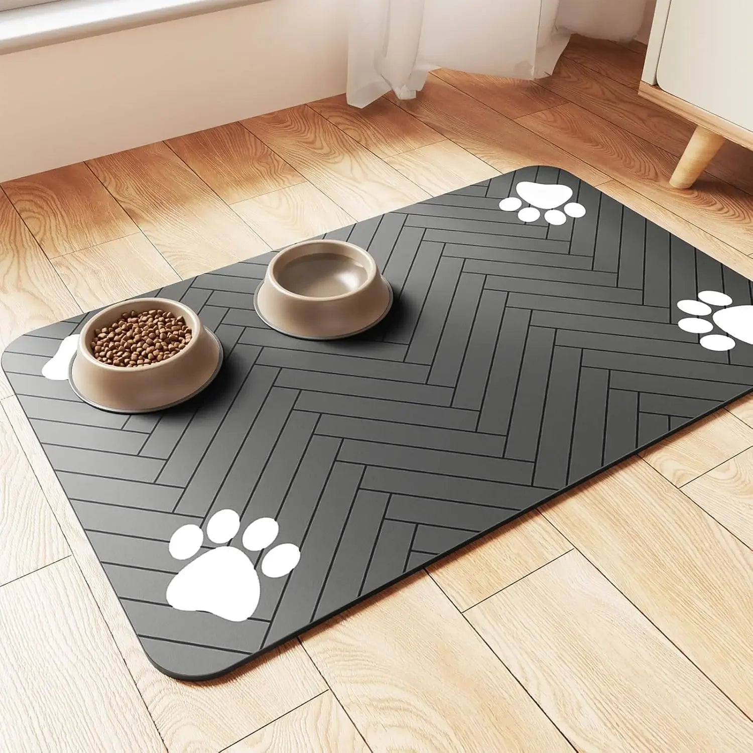 Gray pet mat with paw prints on a wooden floor with pet bowls.